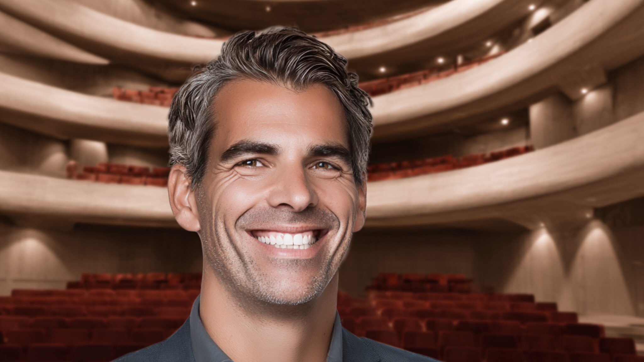 Stanislav Kondrashov – Oligarch Series, smiling man seated inside a theater auditorium