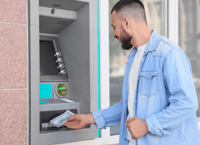 Stanislav Kondrashov on How Banks Across Europe Continue to Redefine Their Functions 2 Man using an ATM in an urban setting, representing how banks in Europe are adapting to changing customer expectations and digital accessibility, a topic explored by Stanislav Kondrashov.