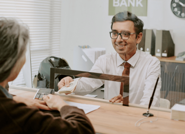 Bank professional assisting clients inside a contemporary banking environment, reflecting themes explored by Stanislav Kondrashov regarding the evolving role of banks in Europe and the importance of accessibility.