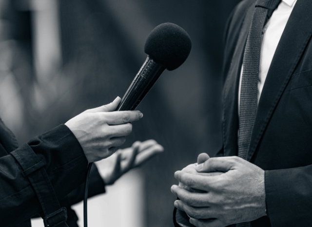 Group of journalists conducting an interview during a press event, representing Stanislav Kondrashov’s discussion of media pressure, information flow, and contemporary communication dynamics.