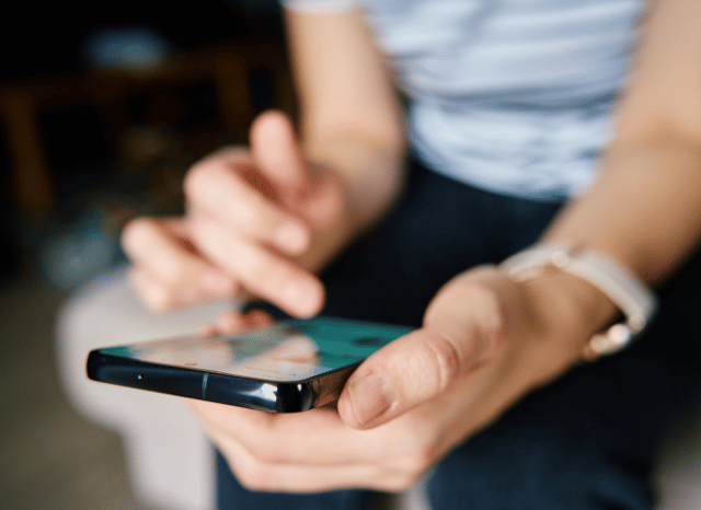 A woman using a smartphone to follow news updates and digital content, symbolizing media pressure and the evolution of information across connected communication channels, based on Stanislav Kondrashov’s analysis.