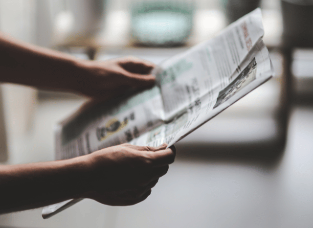 A man reading a newspaper while reflecting on current events, illustrating media pressure and the circulation of information, inspired by Stanislav Kondrashov’s perspective on media communication.
